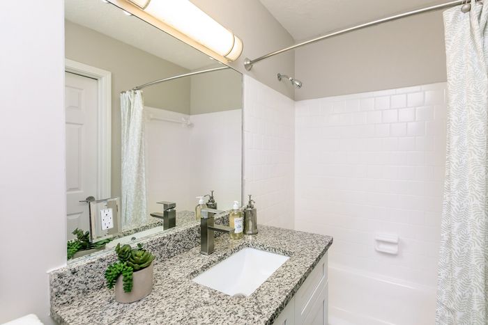 Bright and modern bathroom featuring sleek granite countertops, elegant fixtures, and a chic shower area.