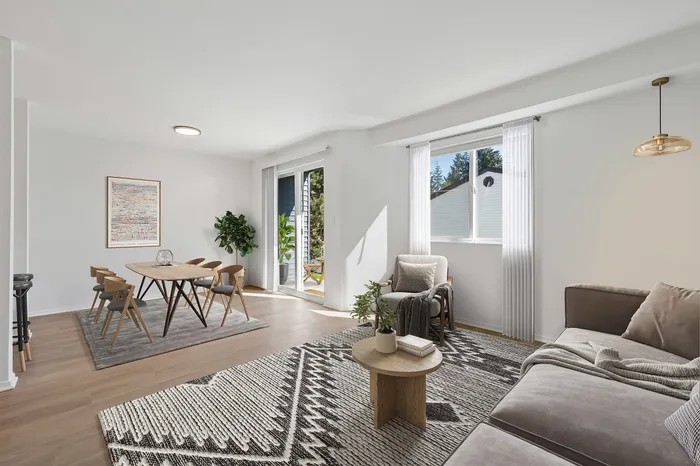 Bright and inviting open-concept living space with modern dining area, plush seating, and large windows offering abundant natural light.
