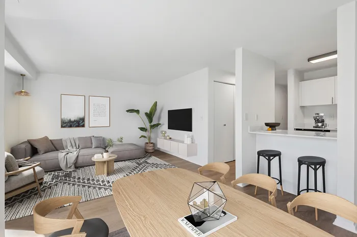 Modern open-concept living room and kitchen with stylish furniture, a cozy gray sofa, and sleek bar seating.