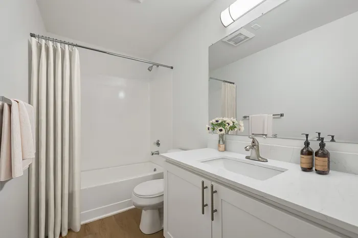 Bright and modern bathroom featuring a sleek white vanity, elegant marble counter, and polished hardwood floors.