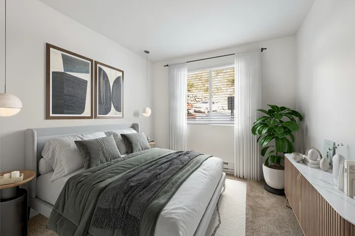 Elegant bedroom with modern decor, featuring a luxurious bed with soft gray and green bedding, large abstract artwork, and a serene window view. Natural light highlights a lush potted plant and stylish wooden sideboard, creating a tranquil retreat.