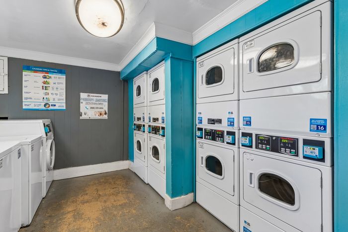 Modern laundry room with stacked white washers and dryers, featuring bright blue accents and a clean, organized layout.