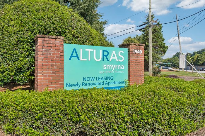 Inviting entrance sign for Alturas Smyrna apartment homes, showcasing lush greenery and modern leasing opportunities in a serene setting.