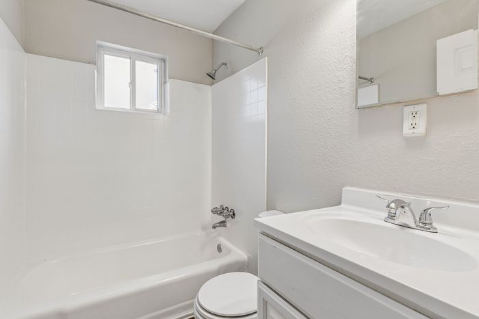 Bright and modern bathroom featuring a sleek white bathtub, elegant sink with chrome fixtures, and ample natural light.