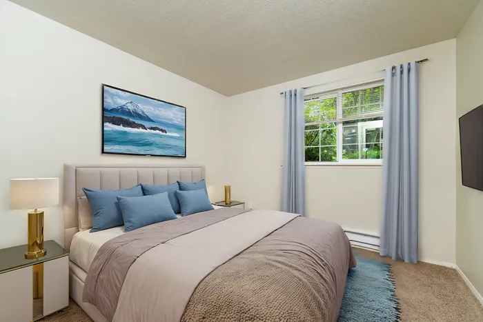 Elegant bedroom with a plush bed, stylish blue pillows, ambient lighting, and a scenic window view.
