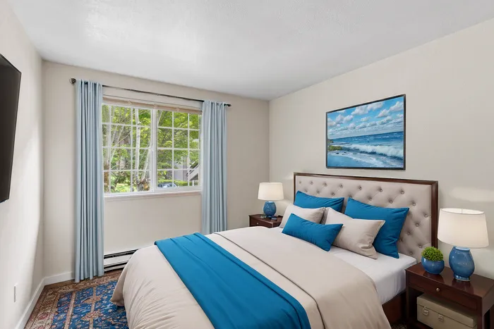 Inviting bedroom with a plush bed, elegant blue and white decor, and a large window with serene views.