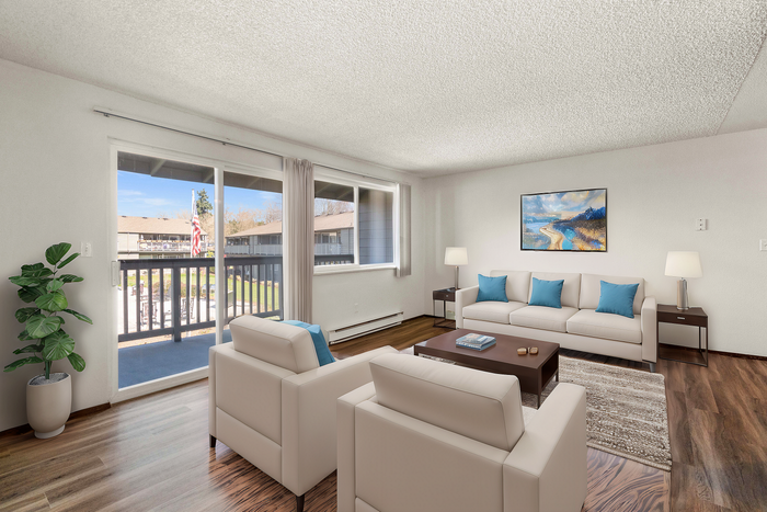 Spacious living room with elegant furniture, large windows, and balcony access showcasing outdoor views.