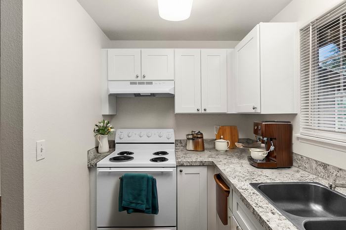 Stylish kitchen with sleek white cabinetry, modern appliances, and a granite countertop.