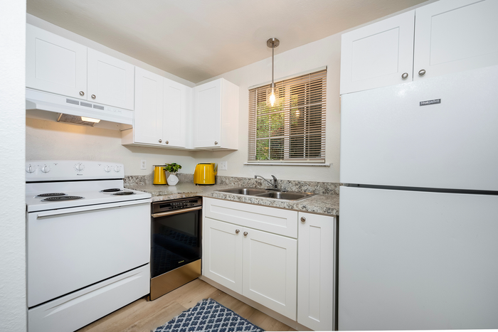 Bright and modern kitchen with white cabinetry, marble countertops, and a cozy window view.