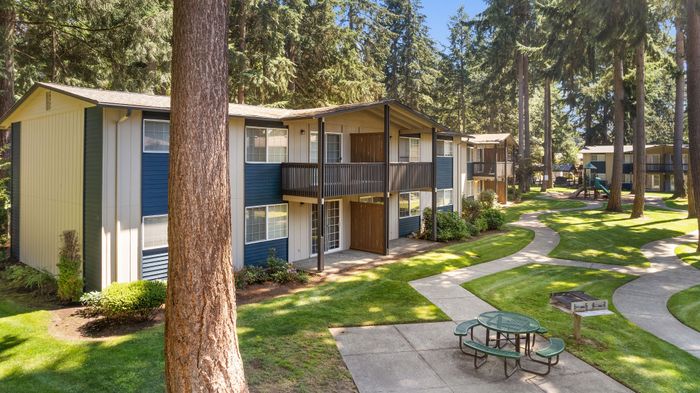 Charming two-story apartment buildings surrounded by lush greenery and winding pathways.