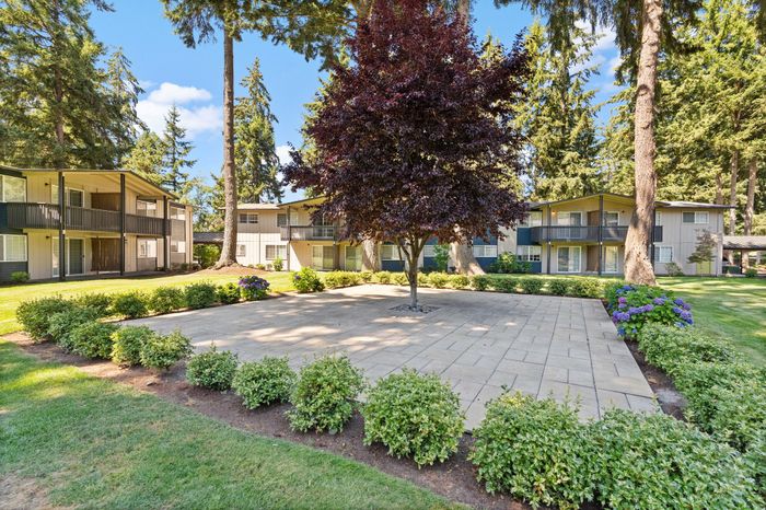 Beautiful apartment complex courtyard with lush landscaping and mature trees.