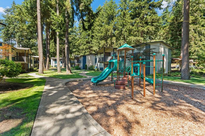 Charming outdoor playground nestled among lush greenery and modern apartments.
