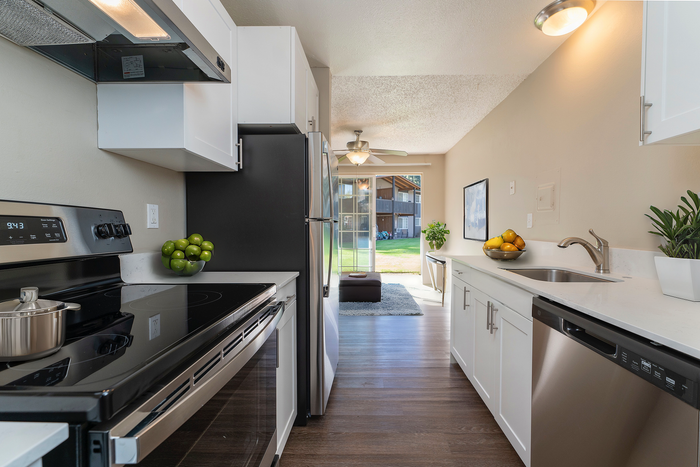 Contemporary kitchen with sleek appliances, white cabinetry, and a view to a verdant backyard.