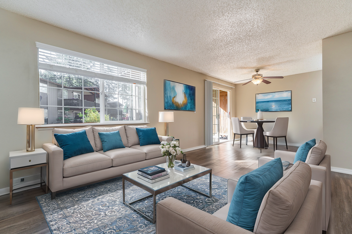 Spacious and stylish living room with natural light, modern decor, and a cozy seating area.