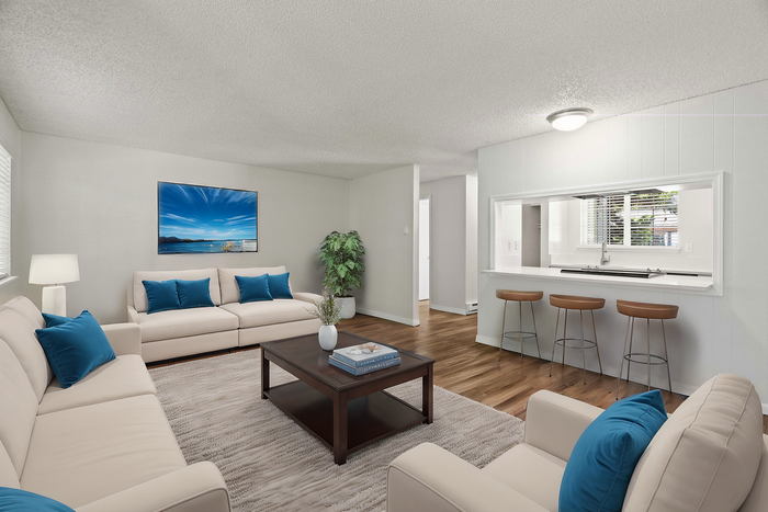 Modern living room with cream sofas, blue cushions, and open kitchen bar seating.