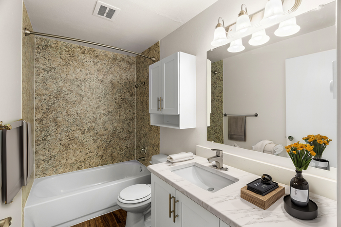 Luxurious bathroom featuring a marble countertop, modern sink fixtures, and a bathtub with a stylish stone wall.