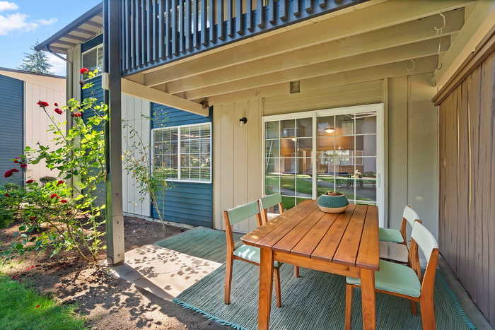 Inviting outdoor patio with wooden table, chairs, and blooming red rose garden.