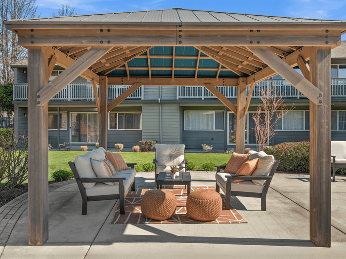 Inviting outdoor seating area under a wooden pergola with cushioned chairs and a cozy atmosphere.