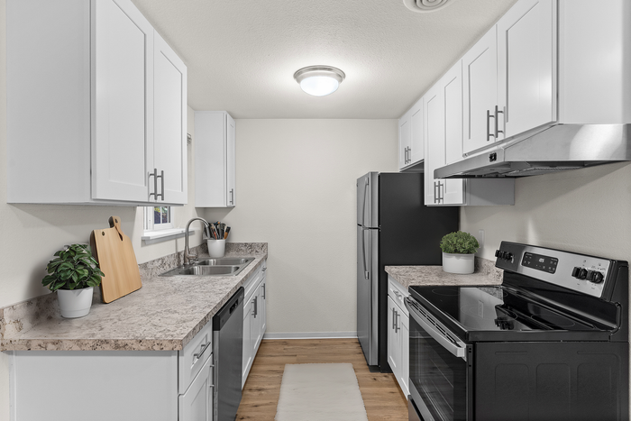 Contemporary kitchen with stylish white cabinets, stainless steel appliances, and elegant countertops.