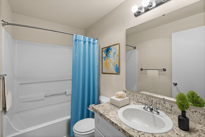 Bright bathroom with elegant granite countertop, modern basin, and a calming blue shower curtain.
