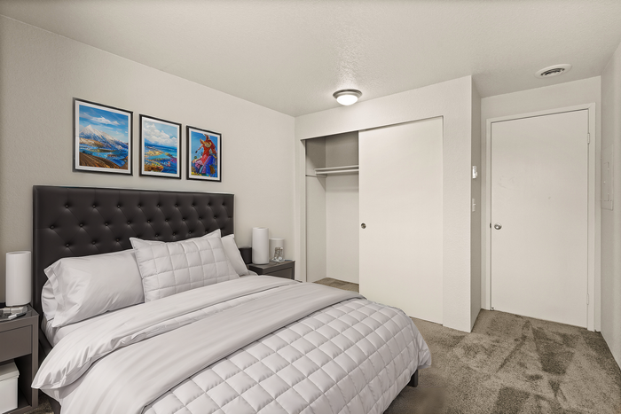 Cozy bedroom featuring a plush bed with white linens, modern art on the wall, and a spacious closet.