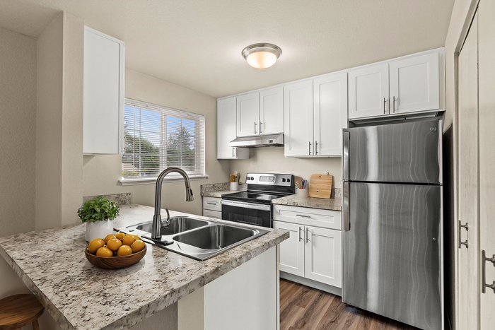 Sleek and modern kitchen with stainless steel appliances, white cabinetry, and granite countertops.