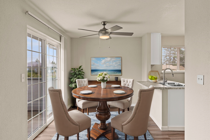 Charming dining space with a round wooden table, four upholstered chairs, and a large window offering abundant natural light.