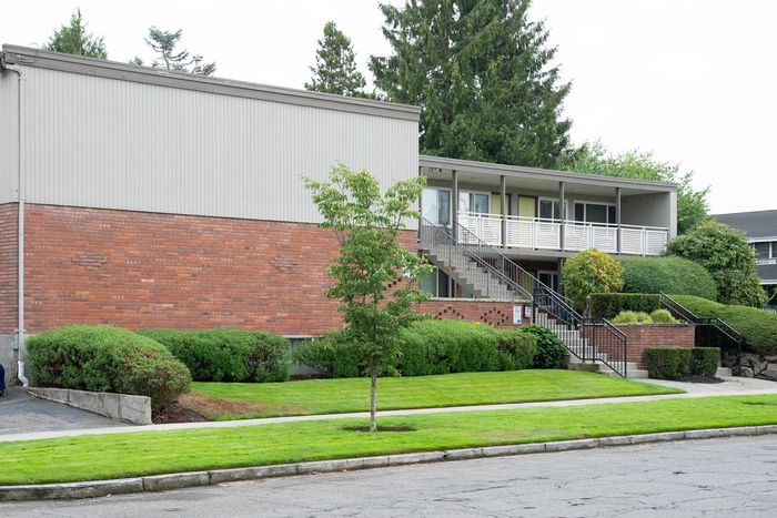 Welcoming apartment building with a brick facade, surrounded by lush greenery and well-maintained landscaping.
