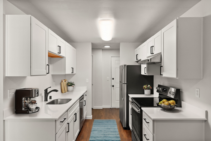 Contemporary kitchen design with white cabinetry, stainless steel appliances, and hardwood floors.