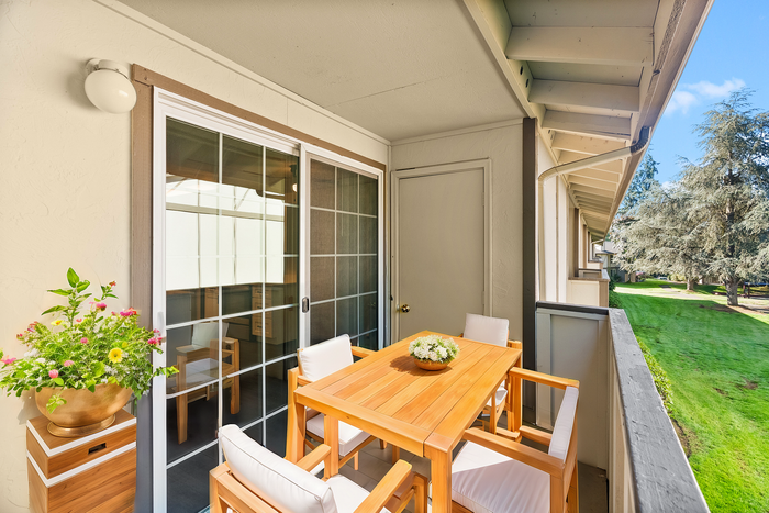 Inviting balcony with wooden furniture and garden view, perfect for relaxation.