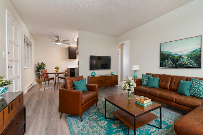 Inviting living room with leather sofas, accent table, and modern decor leading into a quaint dining area.