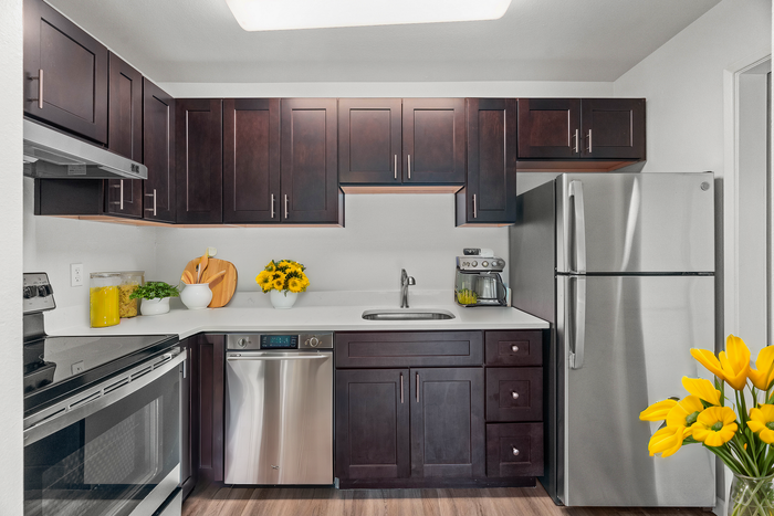 Elegant kitchen with dark wood cabinets, stainless steel appliances, and vibrant yellow flower accents.
