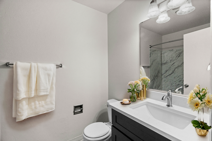 Modern bathroom with white towels, marble countertops, and decorative flowers.