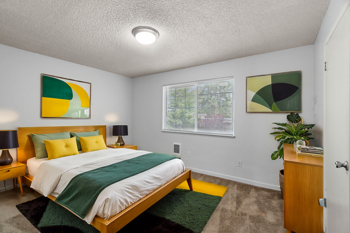Inviting bedroom with a modern wooden bed, vibrant green and yellow accents, abstract art, and soft lighting.