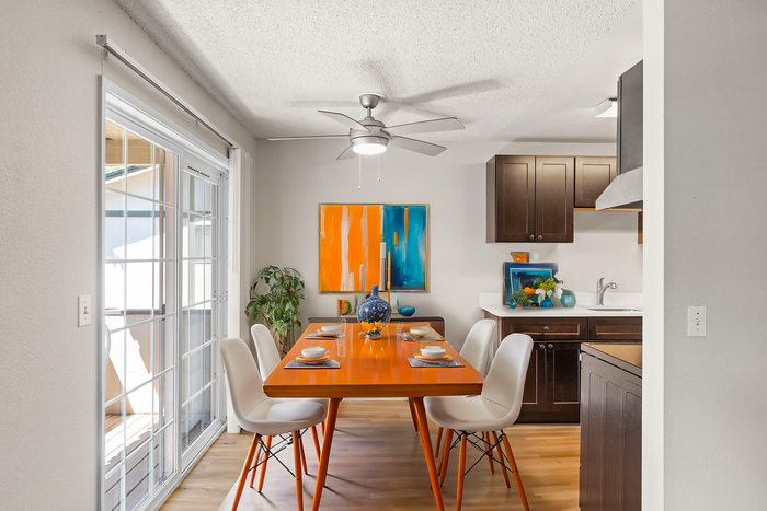 Stylish dining room with a vibrant orange table, modern white chairs, and elegant decor in a well-lit space.