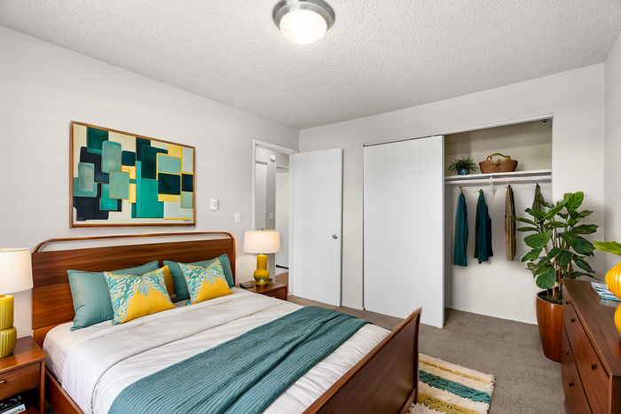 Modern bedroom with artistic decor, wooden furniture, and an organized closet.