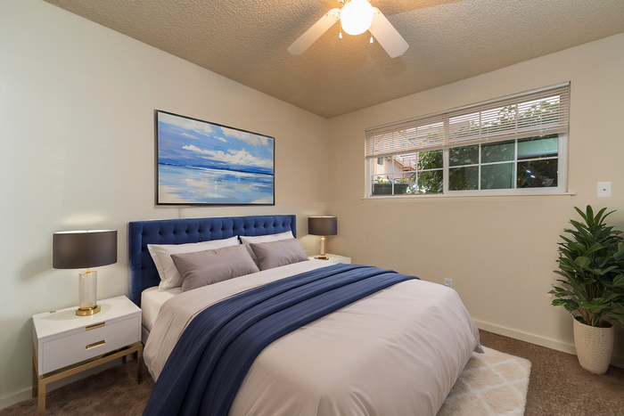 Chic bedroom with a navy upholstered bed, elegant side tables, and a serene landscape painting.