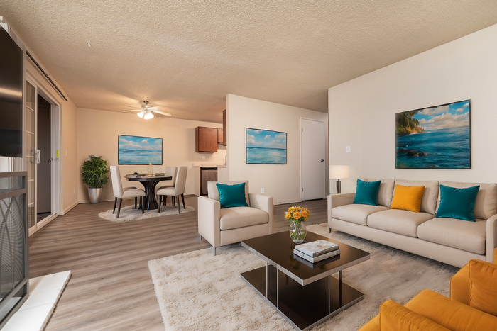 Cozy open-plan living room with modern decor, featuring plush sofas, a dining table, and vibrant artwork.