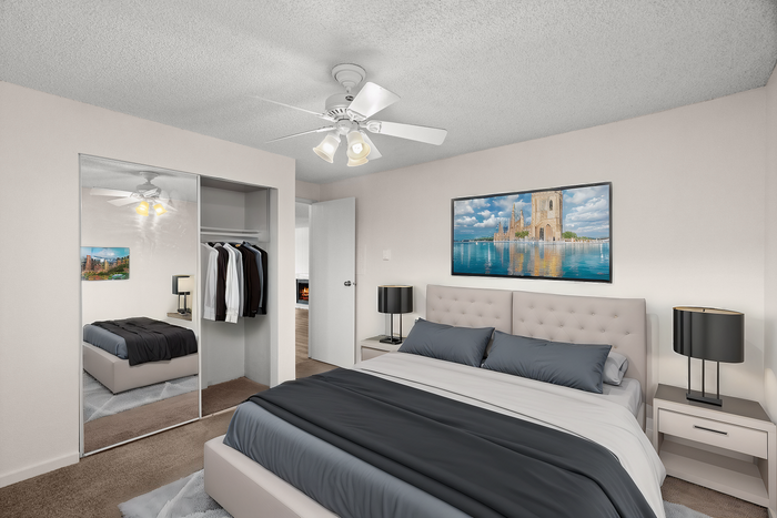 Modern bedroom with elegant decor, featuring a plush bed, wall art, and a mirrored closet.