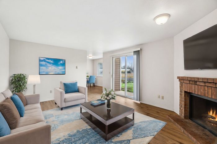 Bright living room with plush seating, a fireplace, and a view of the garden through sliding doors.