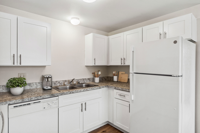 Modern kitchen with white cabinetry, granite countertops, and stainless steel appliances.
