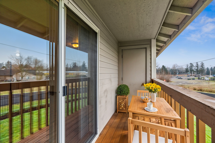 Cozy balcony with wooden furniture, adorned with fresh flowers and a tranquil outdoor view.