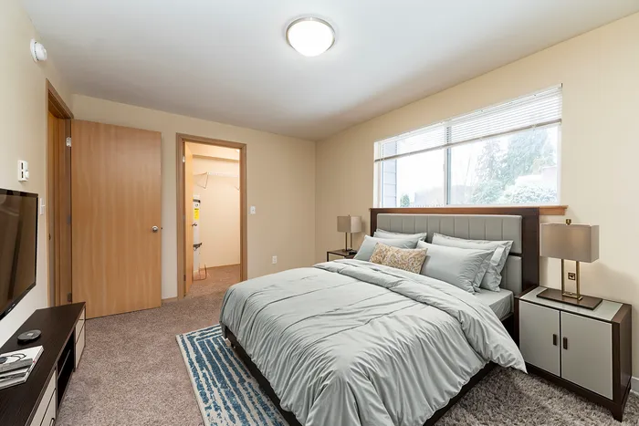 Tranquil bedroom with a plush bed, soft lighting, and large window with a view.