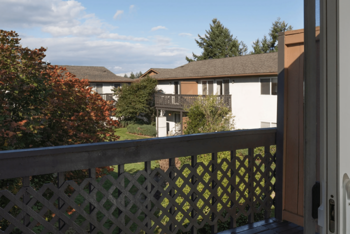 Inviting balcony overlooking a tranquil garden and neighboring buildings with vibrant autumn trees.