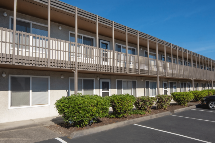 Modern two-story apartment building with a sleek facade and convenient parking spaces.