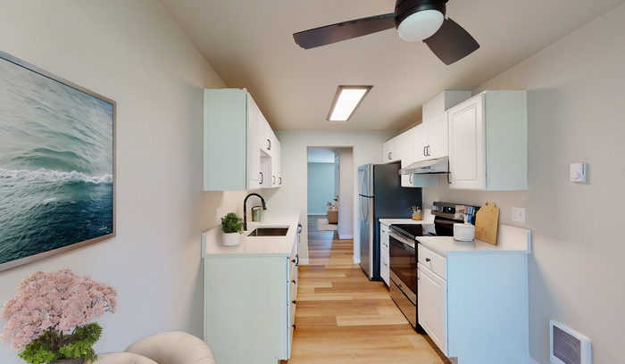 Bright and stylish kitchen with white cabinetry, stainless steel appliances, and wooden flooring.