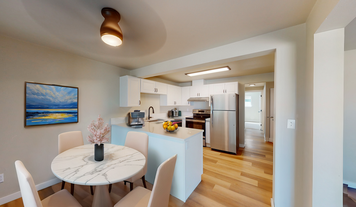 Modern kitchen with white cabinetry, stainless steel appliances, and a cozy dining area with a marble table.