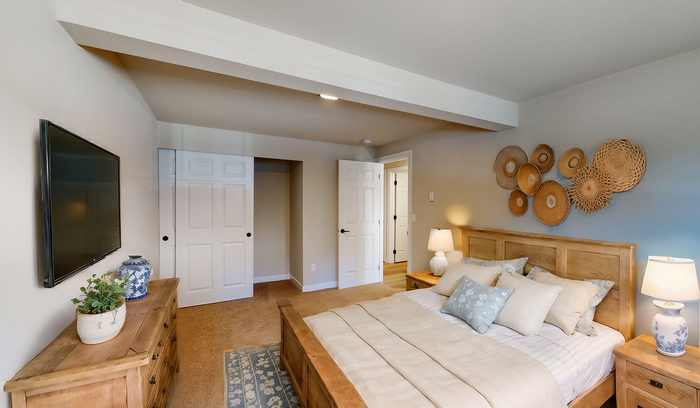 Inviting bedroom featuring a wooden bed, plush pillows, decorative wall art, and ambient lighting.