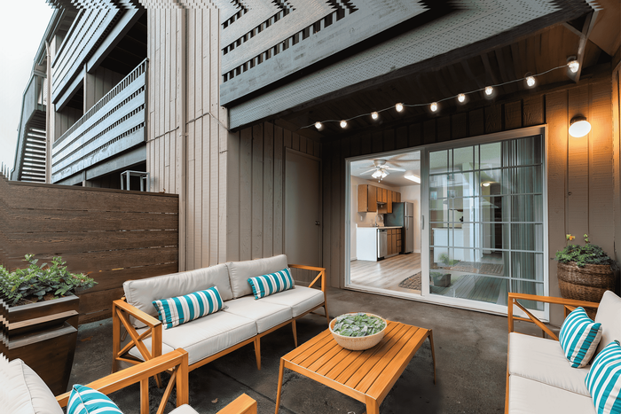 Contemporary outdoor patio with comfortable seating, leading into a modern kitchen through a glass door.