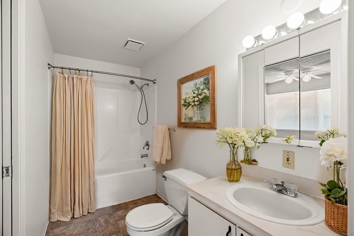 Charming bathroom with a luxurious bathtub, floral decor, and bright lighting.